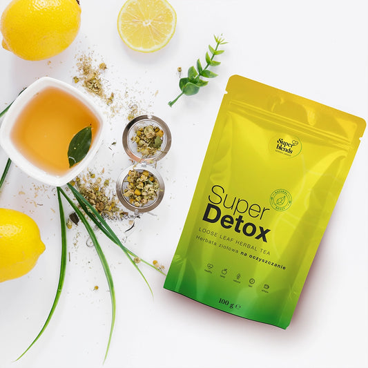 Torebka Super DETOX na białym blacie obok cytryn, ziół i filiżanki naparu