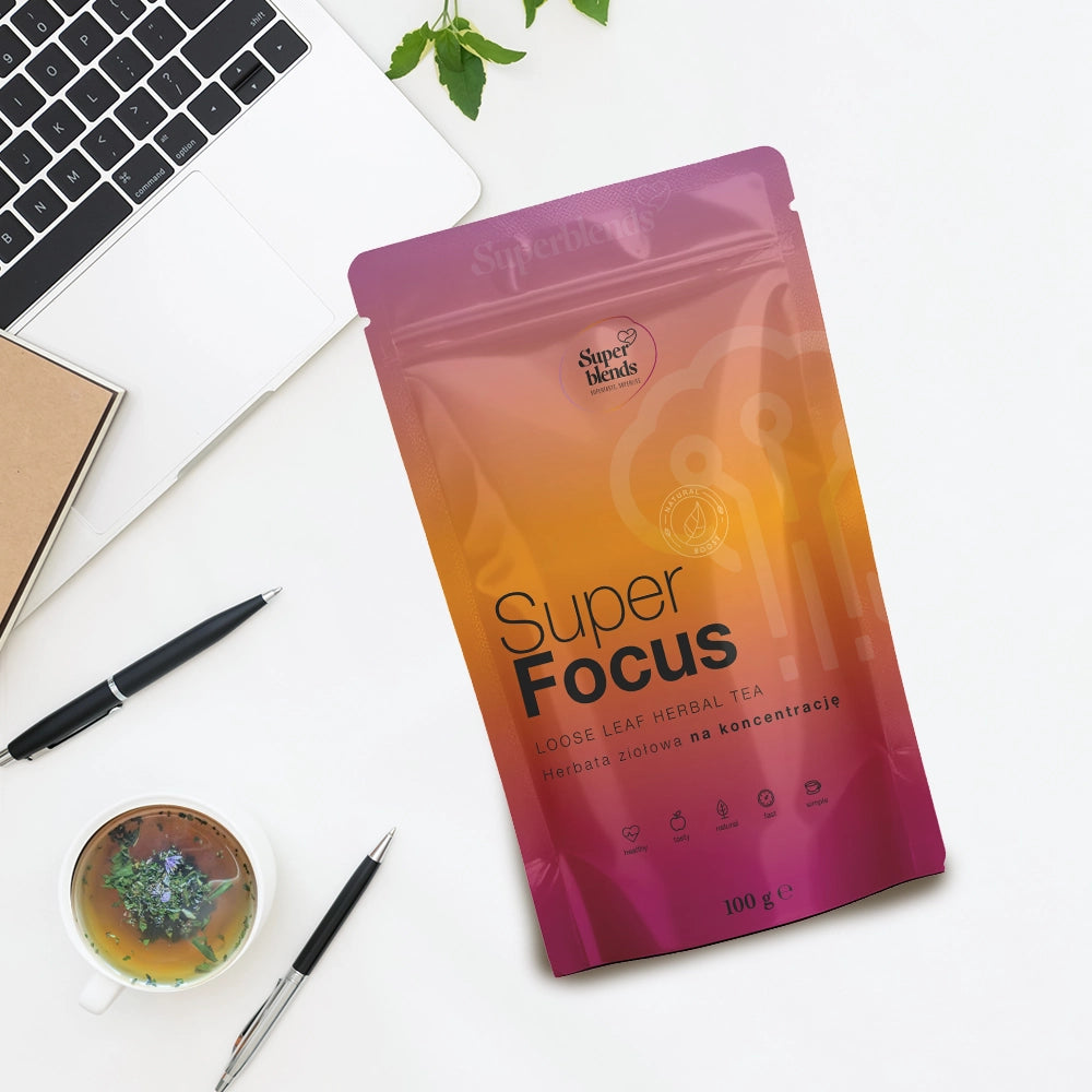 Torebka Super FOCUS na białym biurku obok laptopa, notesu, długopisu i filiżanki herbaty