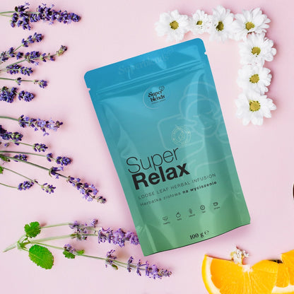 Torebka Super RELAX na różowym tle wśród lawendy, rumianku, melisy i plastrów pomarańczy